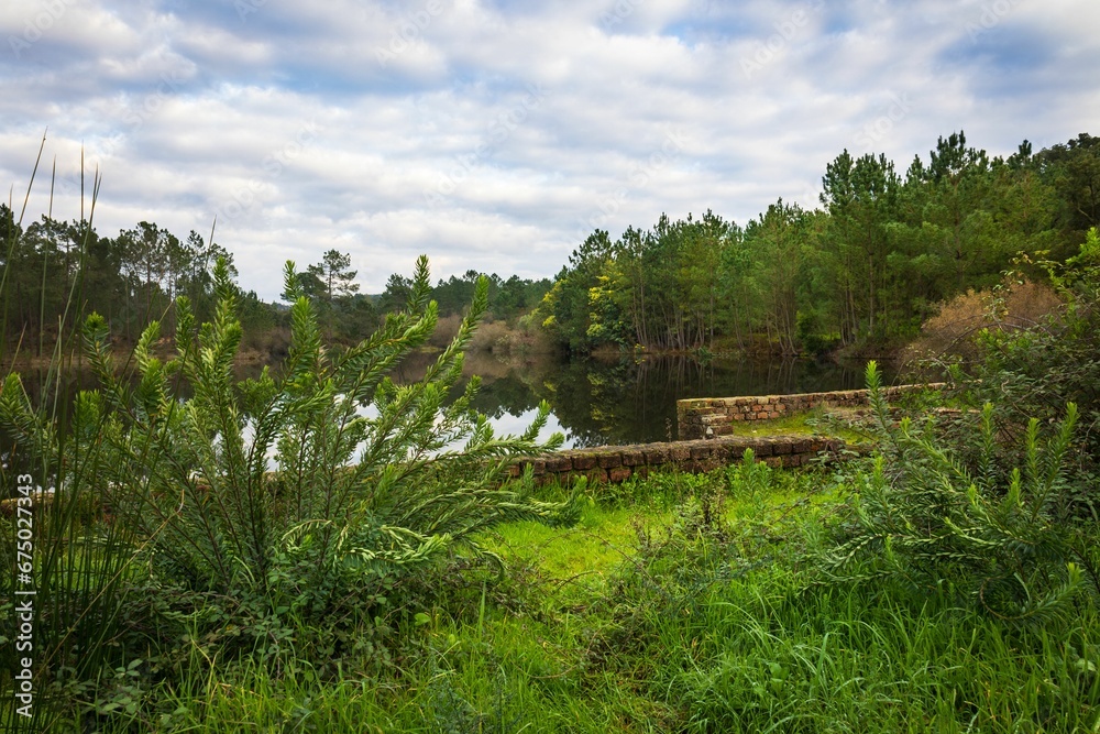 Lake in the woods with beautiful winter blue skies reflections. Bricks water dam in a small village