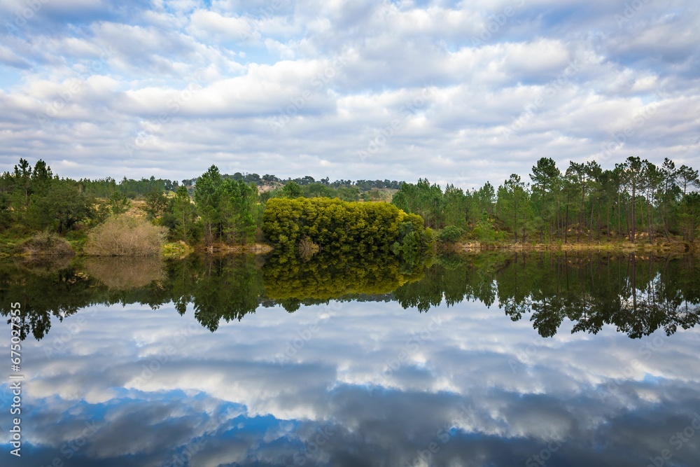 Lake in the woods with beautiful winter blue skies reflections. Bricks water dam in a small village