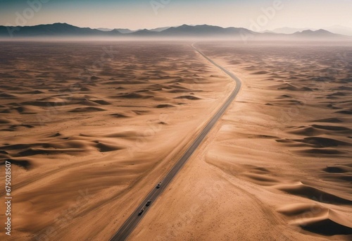 A winding road in a vast desert landscape dotted with golden sand dunes