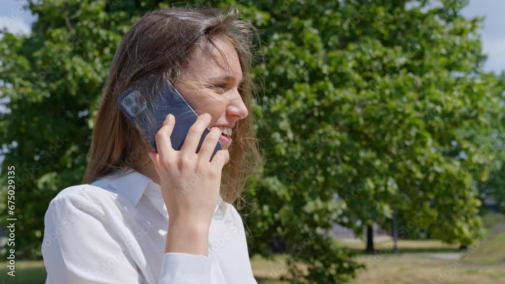 Woman in white elegant shirt talking on phone, windy outdoors weather Woman in white elegant shirt talking on phone, windy outdoors weather