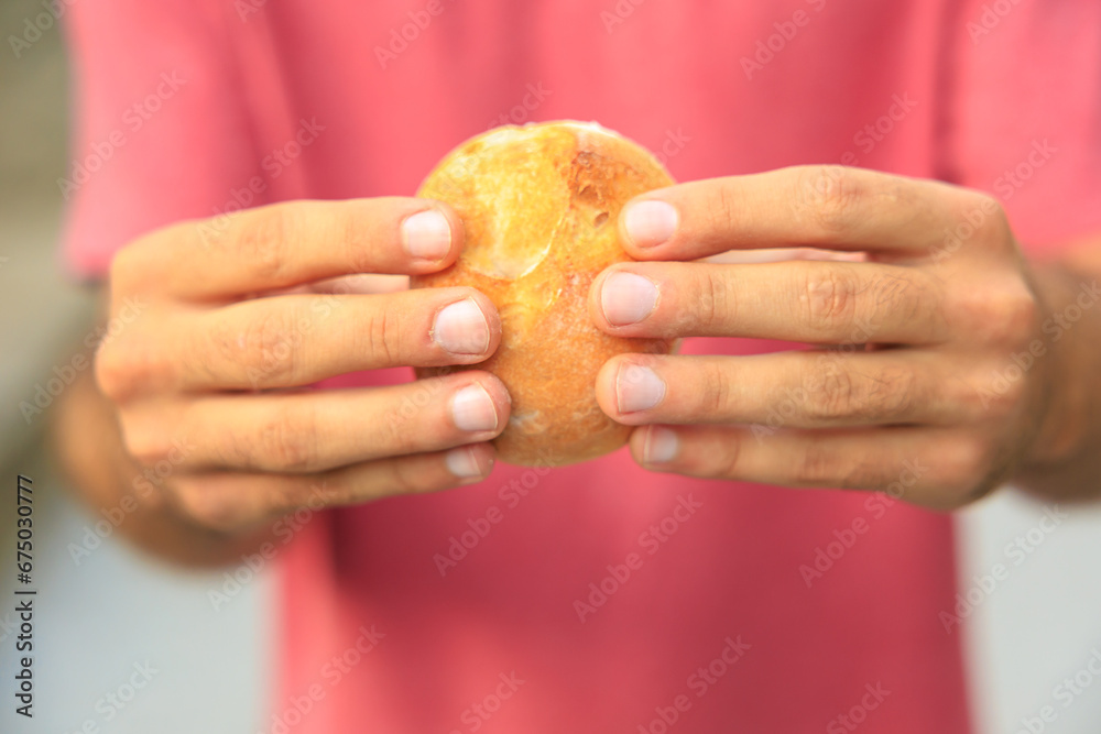 A man's hand holds a round bun, snack and fast food concept. Selective focus on hands with blurred background A man's hand holds a round bun, snack and fast food concept. Selective focus on hands with blurred background