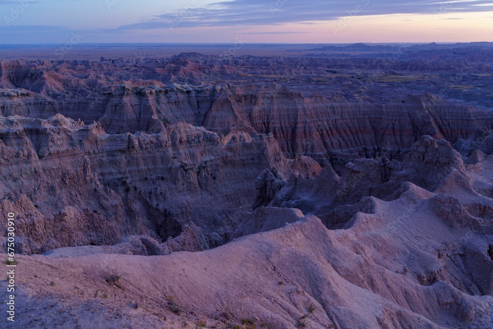 a view over the badlands and plains at sunset time