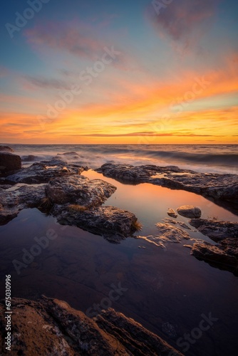 a sunrise over the water in the ocean at low tide
