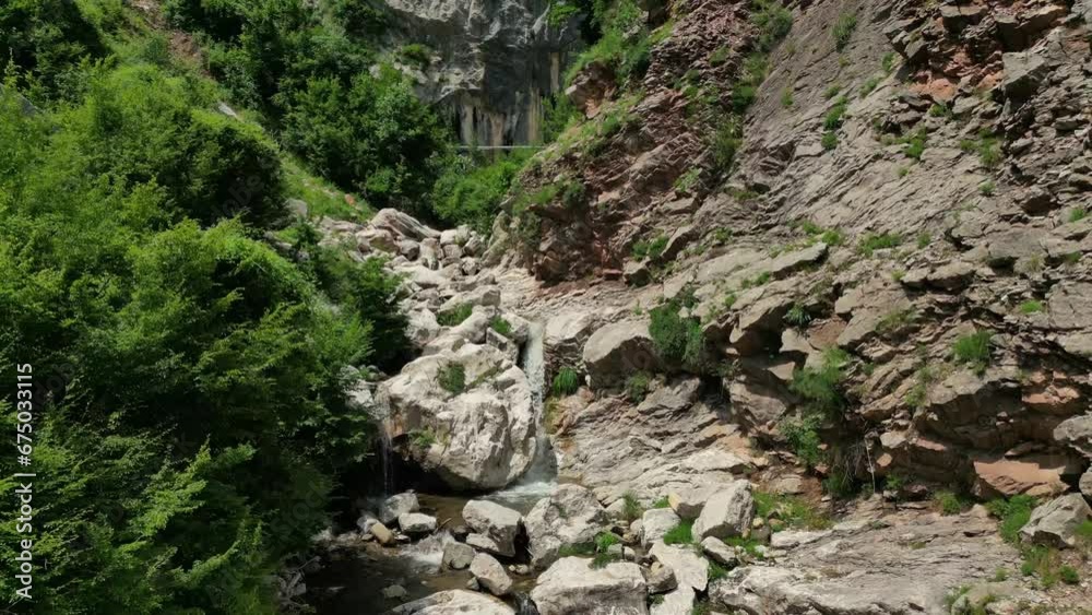 Drone view over rough rocky cliffs surrounded by green vegetation in a wild nature Drone view over rough rocky cliffs surrounded by green vegetation in a wild nature
