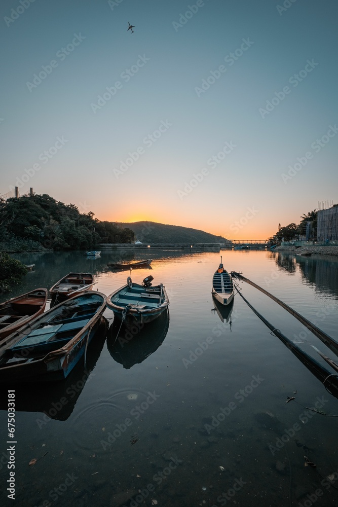 Small watercraft tied to a dock in a tranquil body of water as the sun sets7 Small watercraft tied to a dock in a tranquil body of water as the sun sets7