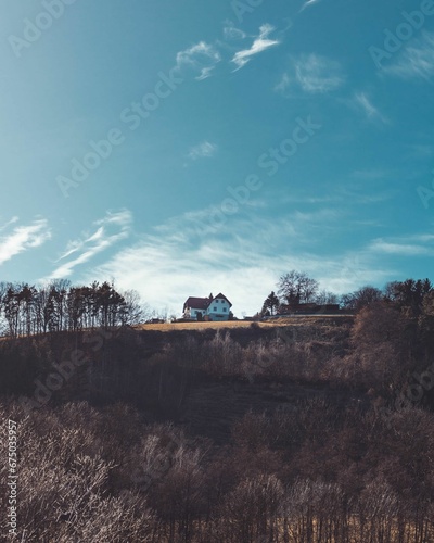 Vertical shot of a house on top of a hill next to Stubenbergsee, Austria photo