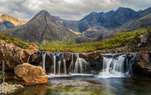 a small waterfall with rocks and green plants in the foreground