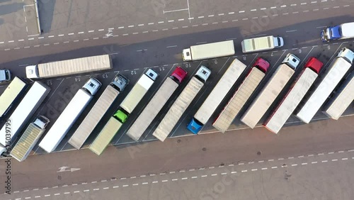 Aerial Shot of Truck with Attached Semi Trailer Leaving Industrial Warehouse Storage Building Loading Area where Many Trucks Are Loading Unloading Merchandise. Shot on Phantom 4K UHD Camera. photo