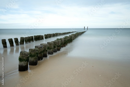 Tranquil beach scene featuring a line of wooden posts resting in the sand of a shoreline