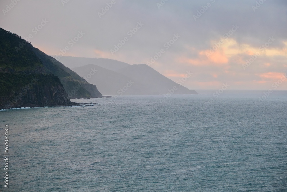 Ocean with fog rolling in and lush hills in the background
