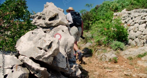 Man walks between rock walls along hiking trail carrying camera as he explores Croatias natural beauty photo
