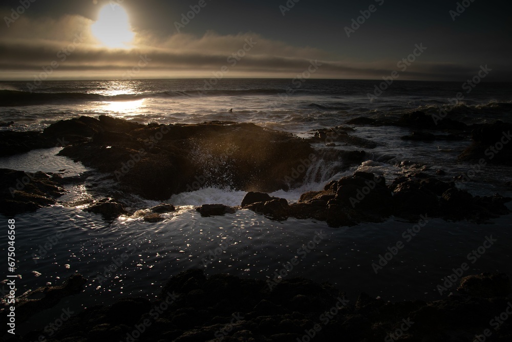 Obraz premium waves crash up against the rocks at sunset on a rocky shore