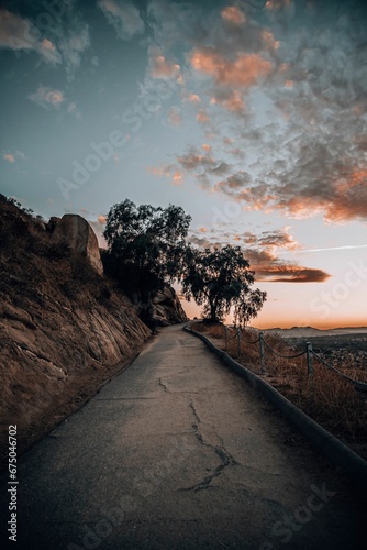 the road by the ocean during sunset and a person is walking along photo