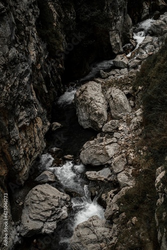 Small waterfall cascading down a rocky ravine in a narrow valley