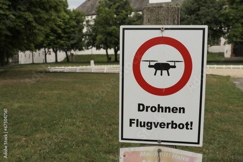 White rectangular sign with red and black text reading 'Drones flight ban' in German beneath it