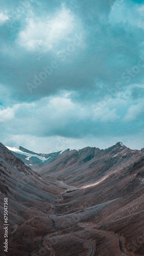 Scenic view of barren mountains under a cloudy sky