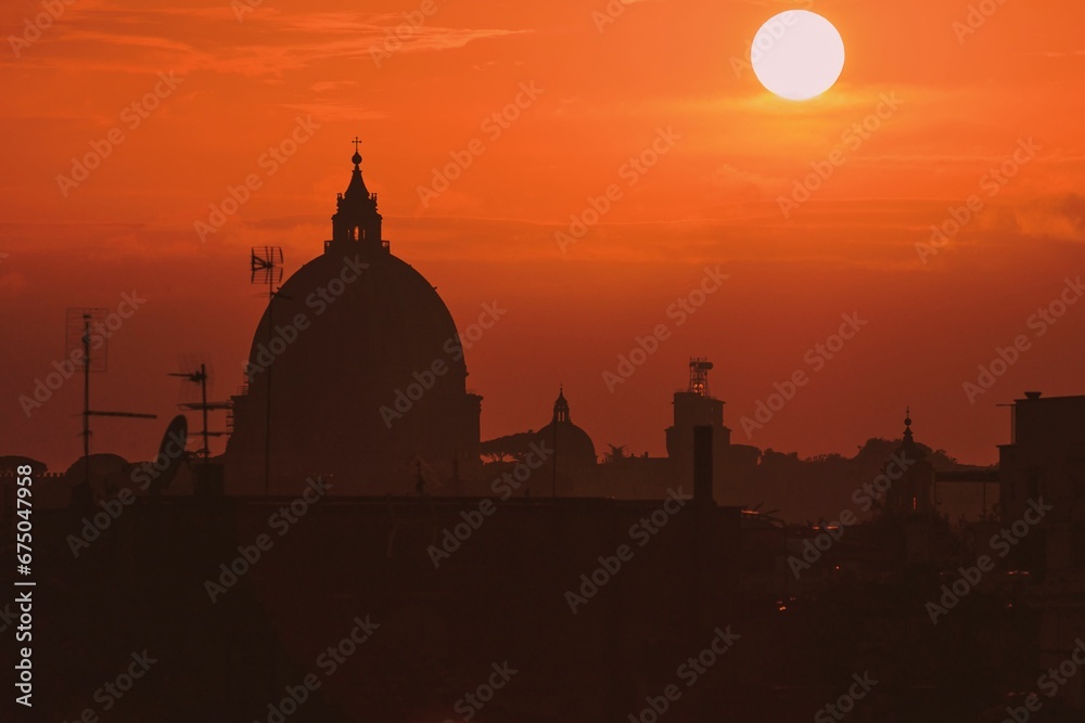 Obraz premium St Peter's Basilica silhouette with an orange sunset sky in the background