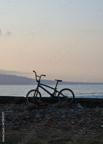 Mountain bike on the beach with the sunrise in the background. © Handoko