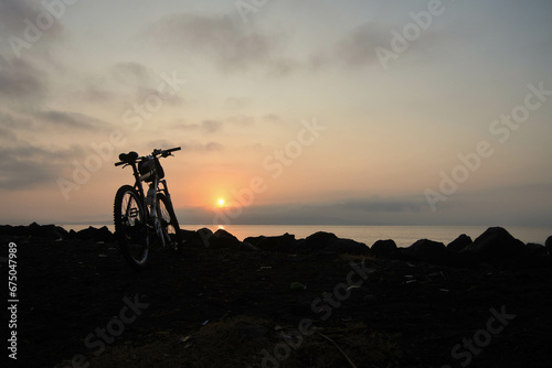 Mountain bike on the beach with the sunrise in the background.