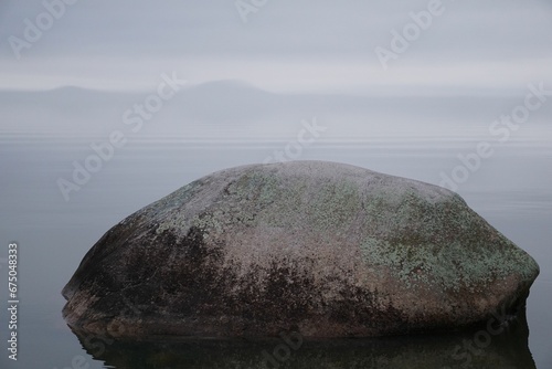 Large mossy rock on the water of Lake Varnen in Sweden photo