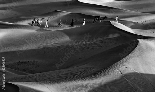 Canvas Print Black and white photo of a group of people enjoying walking in the desert with c
