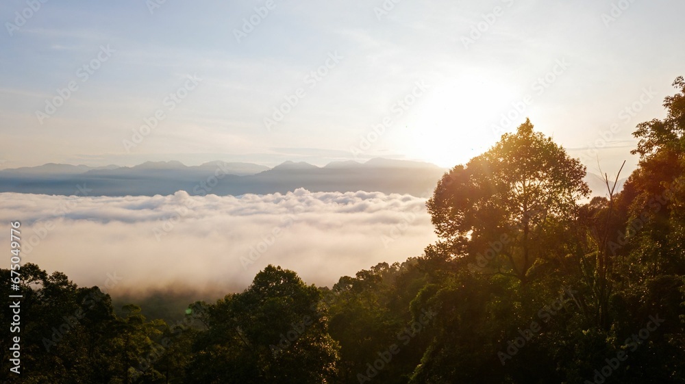 the sun is setting on top of some mountains surrounded by trees the sun is setting on top of some mountains surrounded by trees