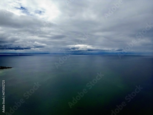 the ocean near an island under cloudy skies and white clouds