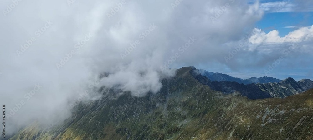 Expansive landscape featuring majestic mountain peaks surrounded by a blanket of clouds.