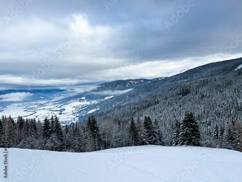 Picturesque winter scene featuring a ski slope surrounded by trees and mountains in the background