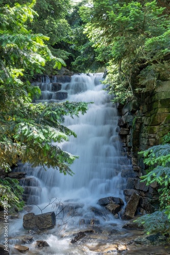 Vertical shot of a waterfall with long exposure in a jungle covered in greenery