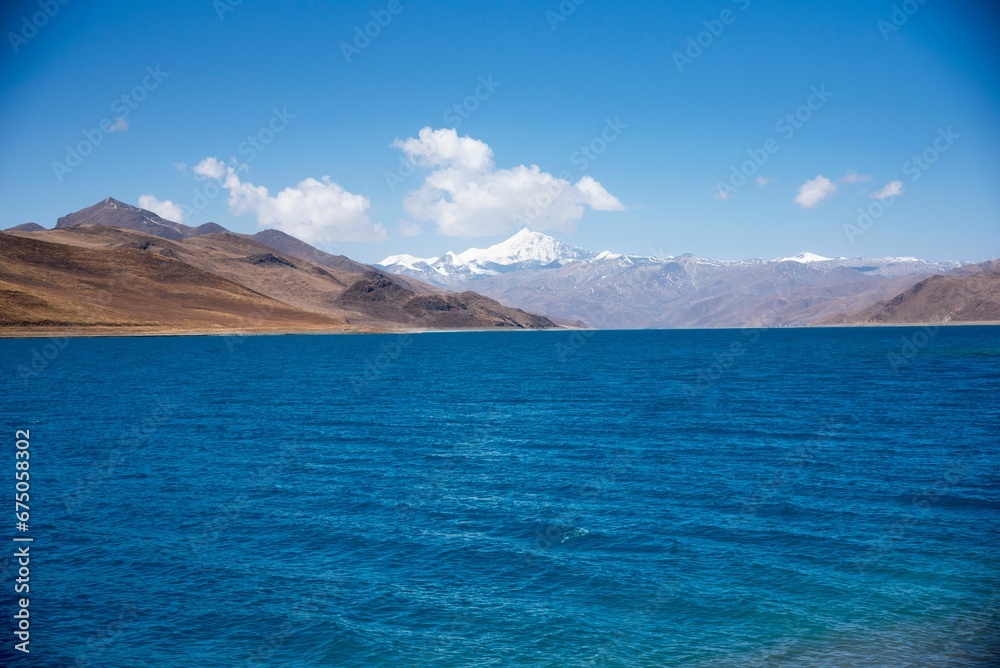Vibrant lake Yamzho Yumco is surrounded by the Himalayan mountains in a tranquil valley