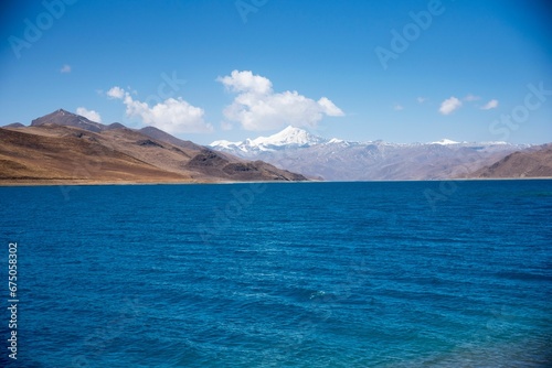 Vibrant lake Yamzho Yumco is surrounded by the Himalayan mountains in a tranquil valley