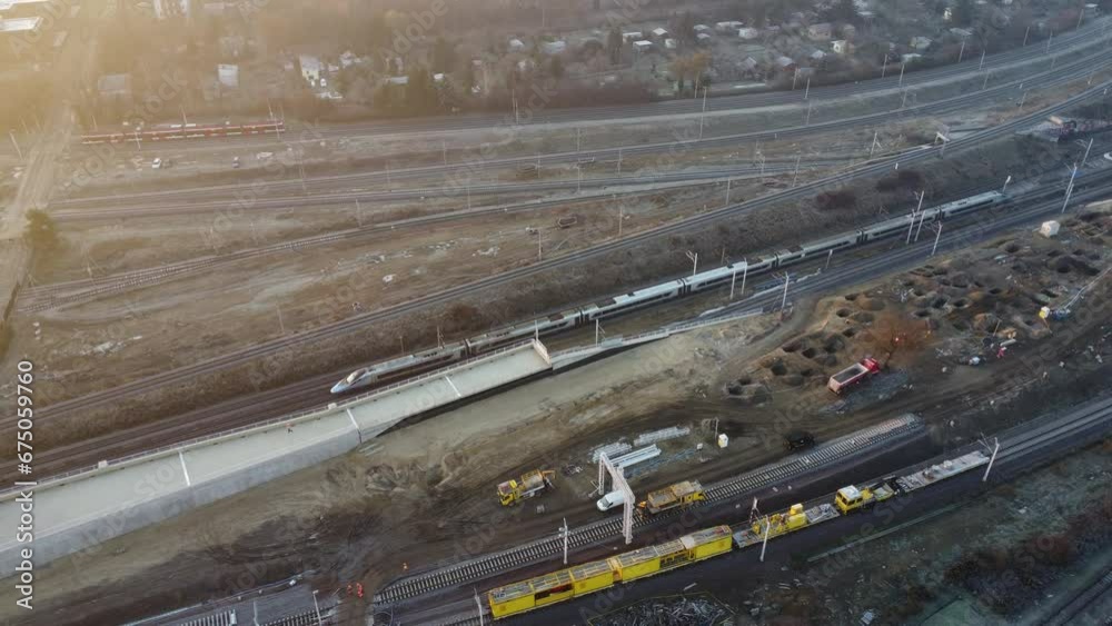 Aerial view of a high-speed train passing through a newly built station still under construction.