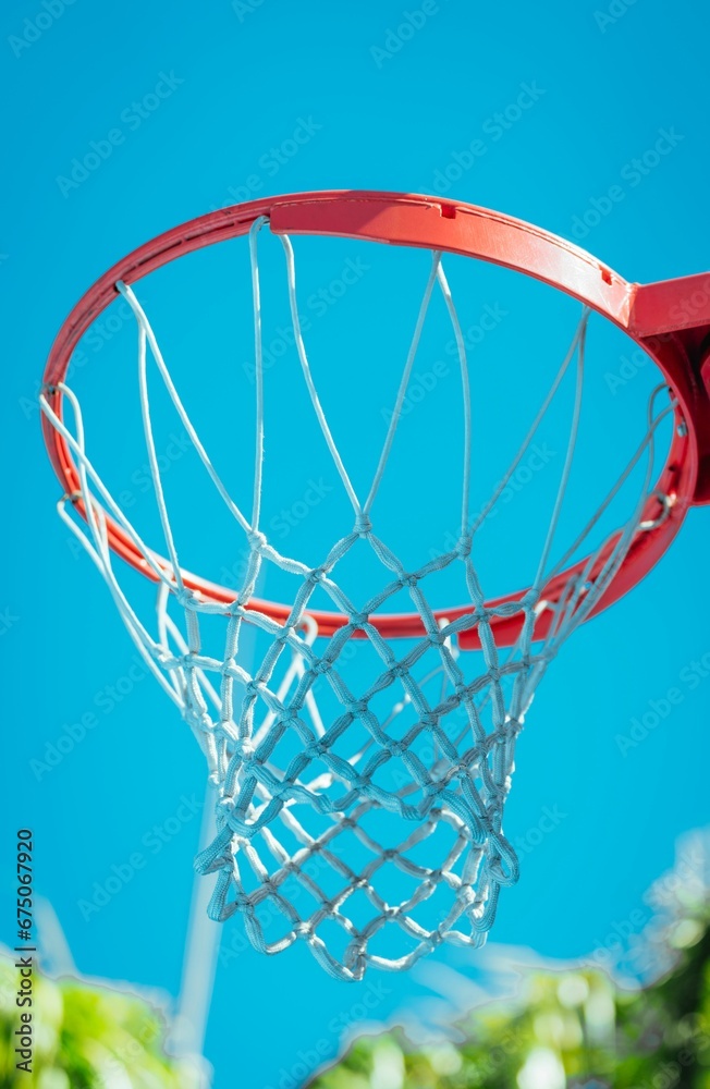 A basketball net in the foreground of a bright blue sky