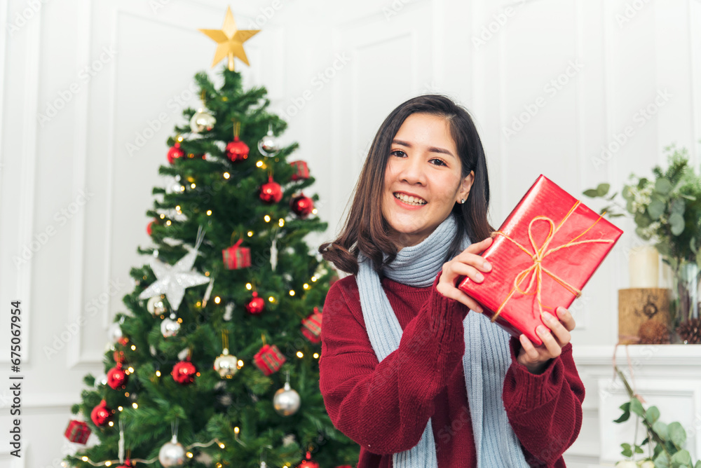 Woman surprise got present gift box on christmas eve. Asian woman holding christmas gift box under xmas tree with smiling face. Woman hands wrap present gift. Merry christmas happy new year concept Woman surprise got present gift box on christmas eve. Asian woman holding christmas gift box under xmas tree with smiling face. Woman hands wrap present gift. Merry christmas happy new year concept