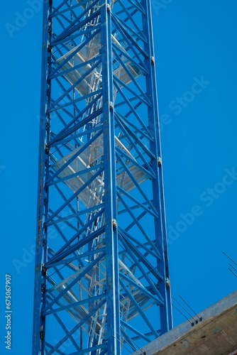 Tall metal blue antenna tower against a blue sky background