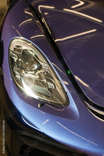 Vertical closeup of the headlight of a modern purple car © Wirestock