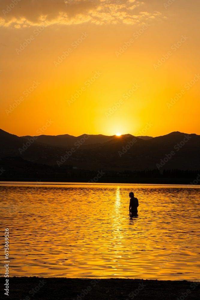 Young adult male on the beach, admiring the sunset