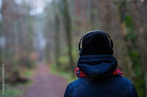 a person in a jacket and headphones looking down a dirt road photo