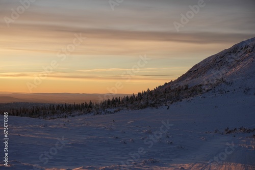 Stunning sunset sky over the snowy trees on a mountain in Dalarna County, Sweden © Wirestock