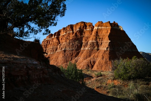a hill of red colored rocks rises above a vast area