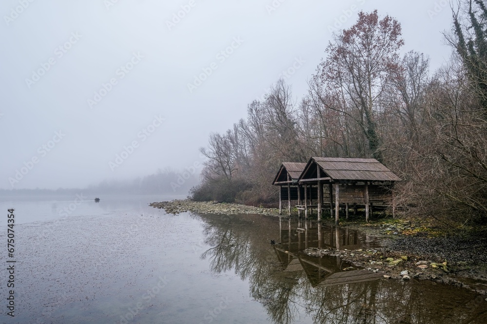 Picturesque log cabin near a tranquil lake in a forest on a foggy day Picturesque log cabin near a tranquil lake in a forest on a foggy day