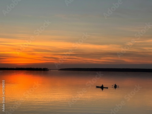 Stunning fiery sunset over a serene lake with boats floating