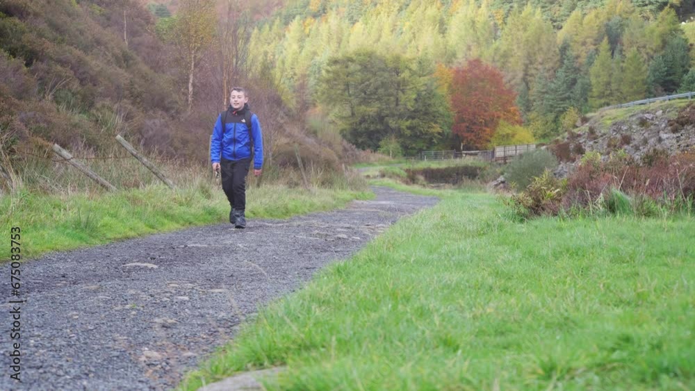 A young boy, with backpack camera and tripod in hand, walking through a tranquil autumn-winter woodland with a meandering stream. Outdoor photography. A young boy, with backpack camera and tripod in hand, walking through a tranquil autumn-winter woodland with a meandering stream. Outdoor photography.