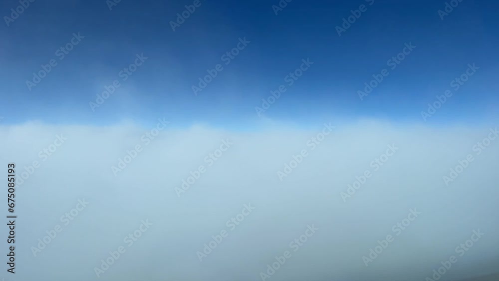 Aerial time lapse shot from an airplane flying through some clouds in a sunny day with a deep blue sky. A pilot’s perspective.