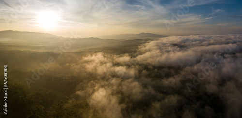 Aerial view of morning sunrise of tropical rainforest at dawn with misty and foggy cloud during summer for outdoor mountain valley landscape