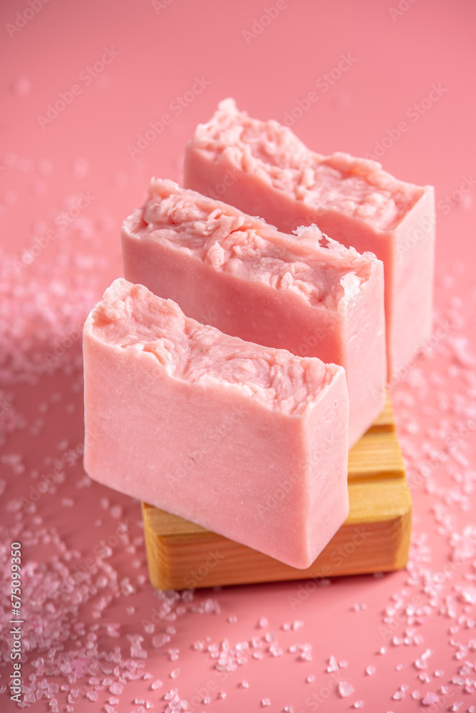 Cute pink pieces of handmade natural soap on a wooden soap dish on a pink background. Modern and safe cosmetic products for skin care and interesting hobby Cute pink pieces of handmade natural soap on a wooden soap dish on a pink background. Modern and safe cosmetic products for skin care and interesting hobby