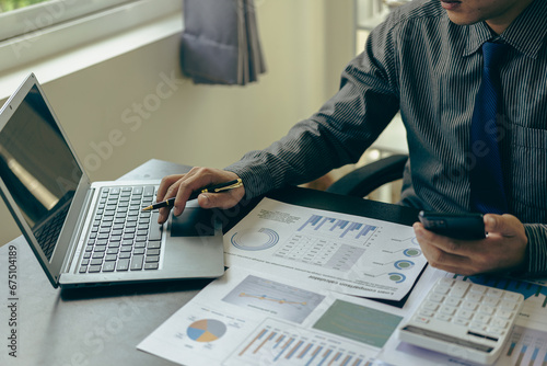 Fototapeta Naklejka Na Ścianę i Meble -  Young Asian businessman working with laptop, checking graphs, company budget reports, production control. Operational inspection cost plus price Close-up pictures