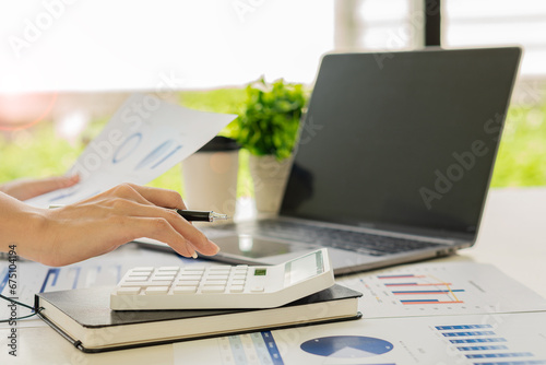 Young Asian businessman working with laptop, checking graphs, company budget reports, production control. Operational inspection cost plus price Close-up pictures