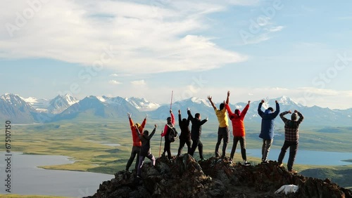 Group of hiker joy with travel success and together raise arms standing on top of high mountain at scenic view. Happy achievement in tourism and summit motivation